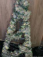 full view of lighted tree form leaning against cabinet