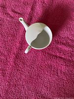 Top view of porcelain invalid feeder cup showing handle, spout, wavy rim