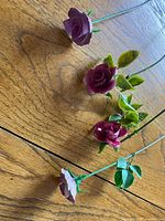Four porcelain long-stem roses on wooden surface