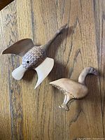 Top view of both carved wooden bird figurines on wood surface