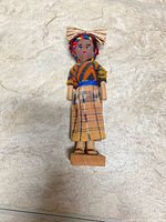 Front view of wooden folk doll standing on base