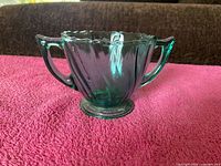 Front view of ultramarine depression glass sugar bowl showing handles, swirl panels and pedestal foot