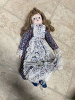 Full view of doll lying flat showing size, dress and overall condition