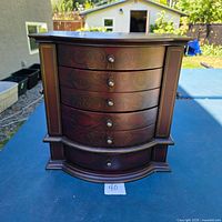 Front view showing five curved drawers and floral detailing