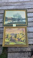 Two framed landscape paintings laid on deck