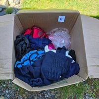 Top view of large cardboard box filled with assorted women’s clothing