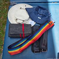 Group shot showing two hats, felt pouch, rainbow strap, pair of weights