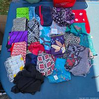 Group shot of roughly 22 assorted scarves laid flat showing variety of colors and patterns