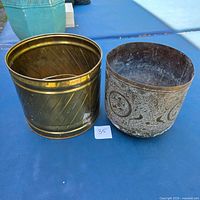 Polished ribbed brass planter beside etched floral brass planter