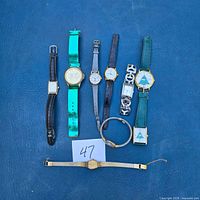 All eight wristwatches displayed on blue surface