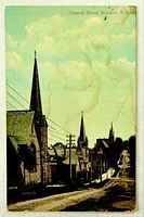 Front image of colour postcard depicting Church Street with churches, utility poles and road
