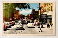 Front of postcard showing colour street scene and title
