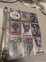 Binder open showing nine trading cards of Toronto Maple Leafs players in sleeve page