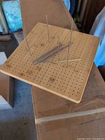 top view of bamboo pegboard with scattered metal pegs