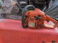 Left side view of Husqvarna 435 chainsaw on red surface