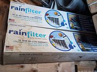 Two RainFilter gutter filtration system boxes showing brand, warranty, coverage and USA origin
