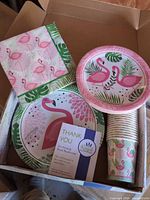Box containing flamingo theme plates, cups, napkins with thank-you card