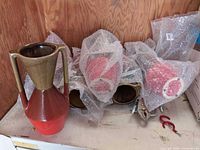 Six vases wrapped in bubble wrap with one unwrapped showing design and colors