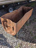 Side view of open-top rusted fuel tank on legs