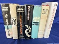 Group shot of seven Agatha Christie related books standing upright