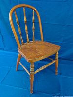 Front three-quarter view of wooden child’s chair showing spindle back, seat and legs