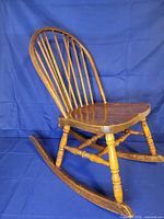 Full view right side of solid wood rocking chair on blue backdrop