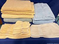 Stacks of yellow, blue towels and beige bath rugs