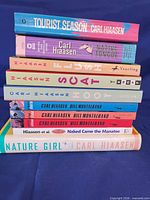 Stack of all ten Carl Hiaasen books showing spines for title identification