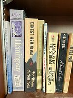 Spines of eight paperback books on shelf