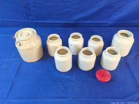 All eight stoneware crocks displayed, showing size comparison and red plastic lid