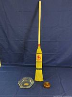 Full view of curling broom, glass ashtray and wooden paperweight
