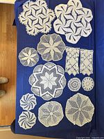 Group of varied round, square and rectangular white crochet doilies on blue background