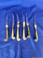 Full view of six steak knives on blue background