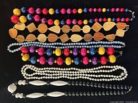 Seven assorted bead necklaces laid flat showcasing colours, shapes and lengths