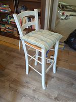 front angled view showing stool design, cushion, ladder back, rush seat