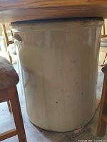Side view of large cream stoneware crock used as table base