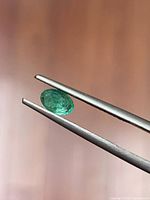 Emerald side view held by tweezers