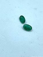 Two small oval emeralds on white background