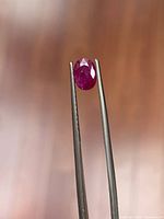Ruby held in tweezers showing top facets