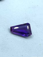 Faceted odd-shaped amethyst on white surface
