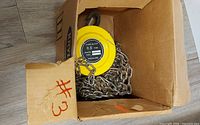 Chain block hoist in box showing label 0.5 ton and chain