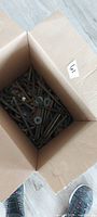 Open box filled with many steel hook bolts, washers, nuts