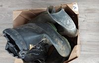 Top view of box containing muddy rubber boots