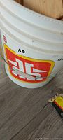 Side view of white plastic bucket with logo