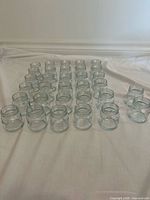 Front view of roughly 30 clear glass Mason jars arranged in rows