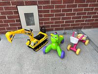 Three ride-on toys arranged side by side on concrete