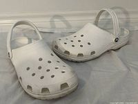Pair of white Crocs Classic clogs showing top, side and heel straps