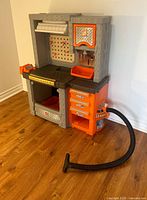 Front view of entire toy workshop showing drawers, cabinet, hose, and work surface