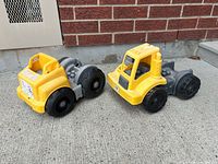 Two Mega Bloks truck bases on concrete showing overall form and colour