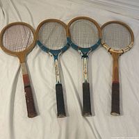 Front view of four vintage wooden tennis racquets laid side-by-side